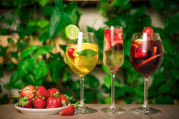 three glasses of sangria from a lot of ingredients on a rustic background.
