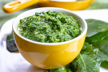 Healthy vegetarian or vegan food, cooked green spinach with cream, ingredient for many dishes like pasta, ravioli or soup