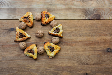 Hamantaschen cookies for Purim and walnuts on a wooden table