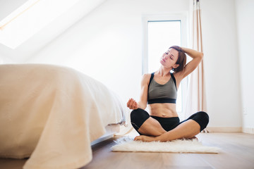 A young woman doing exercise indoors in a bedroom. Copy space.