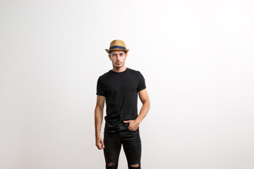A confident hispanic young man with hat and black T-shirt in a studio.