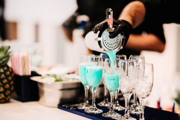 Professional bartender preparing and pouring blue curacao tropical alcoholic cocktail