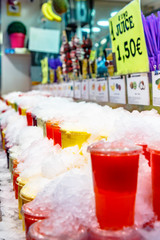 Fresh juice from fruits and vegetables in plastic cups covered with ice