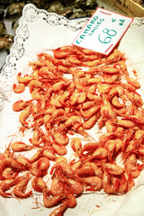 Orange boiled shrimp are on the counter in the fish shop