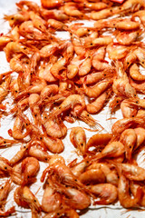 Orange boiled shrimp are on the counter in the fish shop