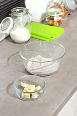 Przygotowanie składników do wypieku ciastek. Masło i mąka w szklanych pojemnikach stoją na...