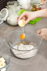 Kobiece dłonie podczas rozbijania jajka kurzego. Oddzielanie żółtka od białka.  Dodawanie jajka do składników przygotowanych do wypieku ciastek. - obrazy, fototapety, plakaty