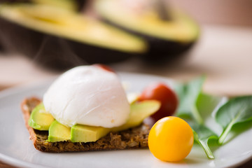 Healthy breakfast with wholemeal toast and benedict eggs with green salad and avocado