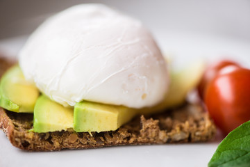 Healthy breakfast with wholemeal toast and benedict eggs with green salad and avocado