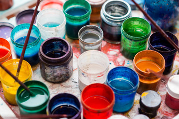 Jars of paint are on the table next to brushes for painting with Ebru technique