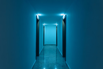 An empty hotel corridor, blue mysterious light in an empty room. The corridor with four doors. The concept of choice.