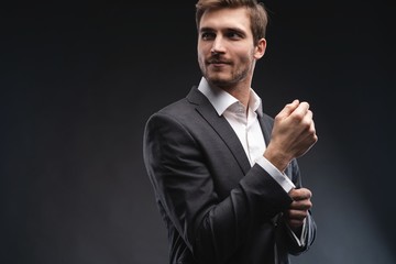 Perfect to the last detail. Handsome young businessman adjusting his sleeves while standing against...