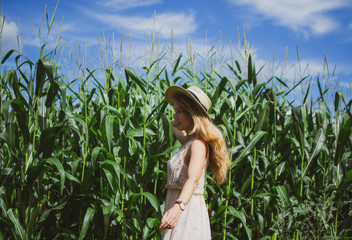 Beautiful woman with long blond hair in hat walking in cornfield, summer, Latvia