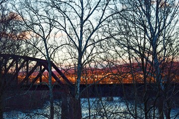 Trestle over river,  in front of sunset town, behind trees