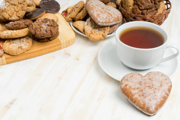 romantic tea party on Valentines day. sweet heart shaped cookies and cup of tea on white wooden table. copy space