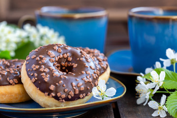 Chocolate donuts and cups of tea