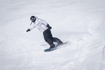 Young guy snowboarder is riding with snowboard from powder snow hill .