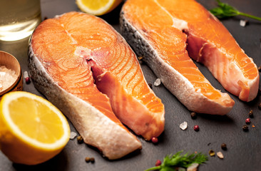 Raw salmon steaks with spices, salt and lemon on the background of old stone