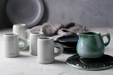 Set of grey rustic coffee cup handcraft and blue ceramic cream jug against shabby grey wall. Natural  handmade crockery tableware - Powered by Adobe