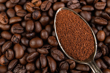 Dark coffee beans on the kitchen table. Ground coffee placed on a silver tob.