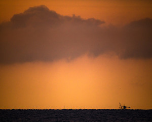 朝の海。雲と水平線の向こうの船影