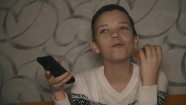 teenager watching television and eating fast food