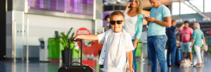 Let journey begin. Portrait of cute couple with their son at airport walking down hall with suitcases