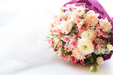 Wedding bouquet made of alstroemeria and white roses in lilac craft paper