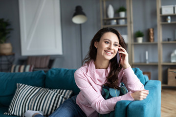 Happy cheerful young woman talking on the phone at home