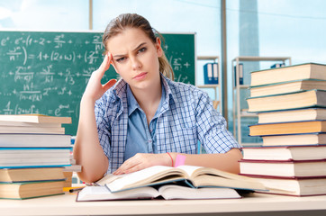 Female student with many books sitting in the classroom