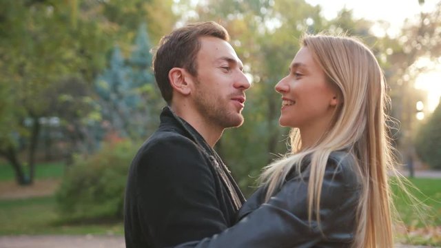 Happy young couple stand hugs in park smile having fun outdoors laughing joyful girl girlfriend nature people relationship summer autumn young beauty happiness love man portrait slow motion close up