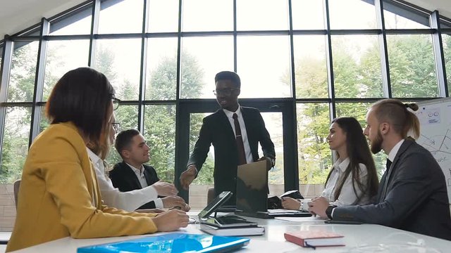 Meeting on the conference afro american and caucasian successful business colleagues who are shaking hands having conversation and exchange knowledge financial reports in office