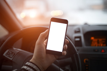 Close-up, hand of man holding smartphone with mockup on background of car dashboard.