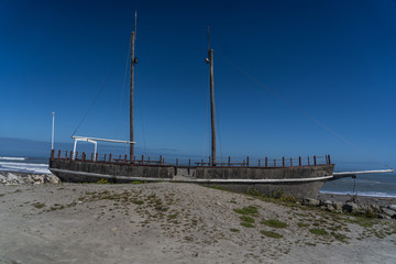 old boat on the beach of hotikita in New Zealand, old broken sailing boat on the beach, hotikita beach with blue sky in the background