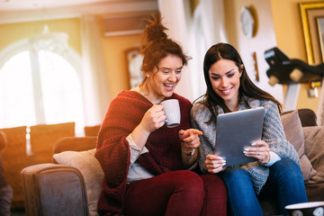 Obraz premium Two female friends watching movie on laptop at home