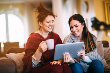 Fototapeta na wymiar Two female friends watching movie on laptop at home