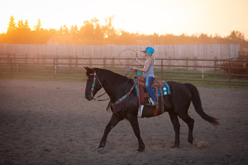 girl riding black horse roping calves © Kimberly