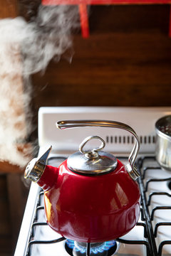 Red tea kettle steaming on stove