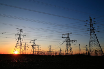 A high-voltage tower in the setting sun against the sky