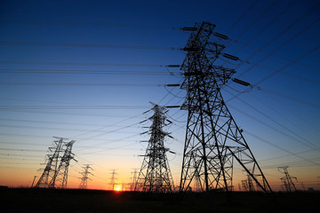 A high-voltage tower in the setting sun against the sky