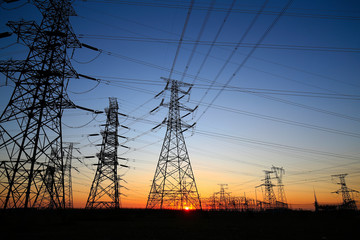 A high-voltage tower in the setting sun against the sky