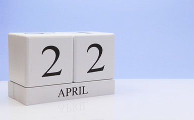 April 22st. Day 22 of month, daily calendar on white table with reflection, with light blue background. Spring time, empty space for text