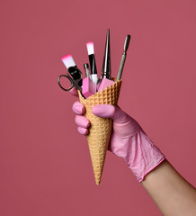 Manicure and pedicure abstract concept. Hand hold  waffles cone with instruments for nails salon...