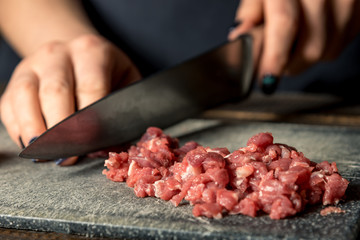 chef hands cut red meat on a board
