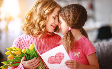 happy mother's day! child daughter   gives mother a bouquet of flowers and postcard.