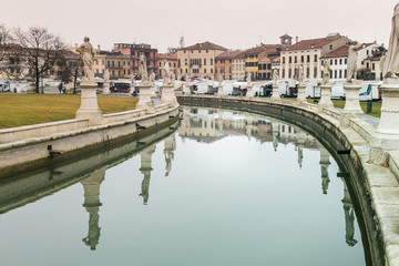 Fototapeta na wymiar Statues reflect on canal water in Prato della Valle Square in Padua, Italy