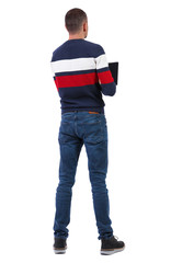 Back view of a man who is standing with a laptop.