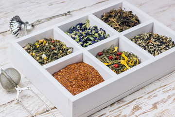 Assortment of dry tea in white wooden box.