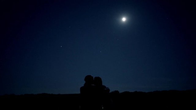 Couple kissing at night under the moonlight