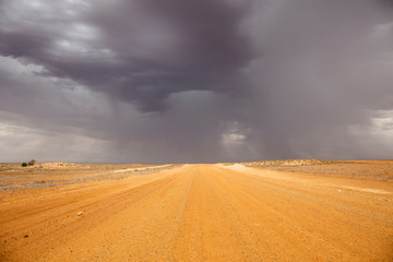 Fototapeta na wymiar Oodnadatta Track, South Australia; yellow dirt road with storm clouds and horizon
